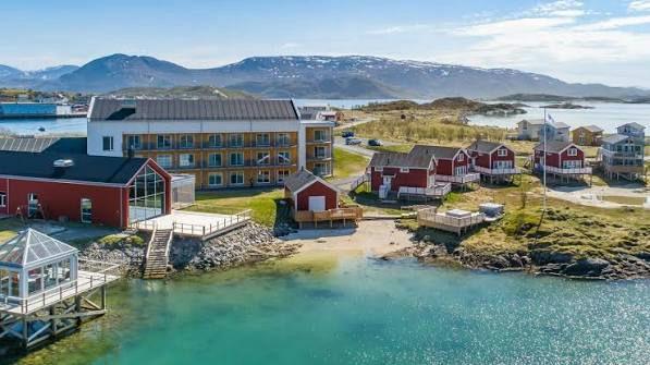 Sommarøy Arctic Hotel beside clear turquoise water and the island coastline